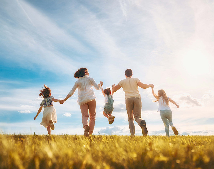 Familie läuft gemeinsam über eine Wiese